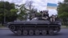 UKRAINE – Ukrainian serviceman wave a flag with writing reading in Ukrainian "Glory to Ukraine", top, and "Death to the enemies" as they ride atop of a tank in the Kharkiv region, eastern Ukraine, May 16, 2022